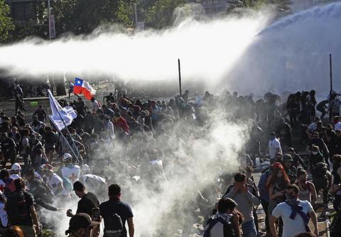 Demonstrators run from police launching water cannons and tear gas in Santiago © 2019 AP Photo/Esteban Felix 